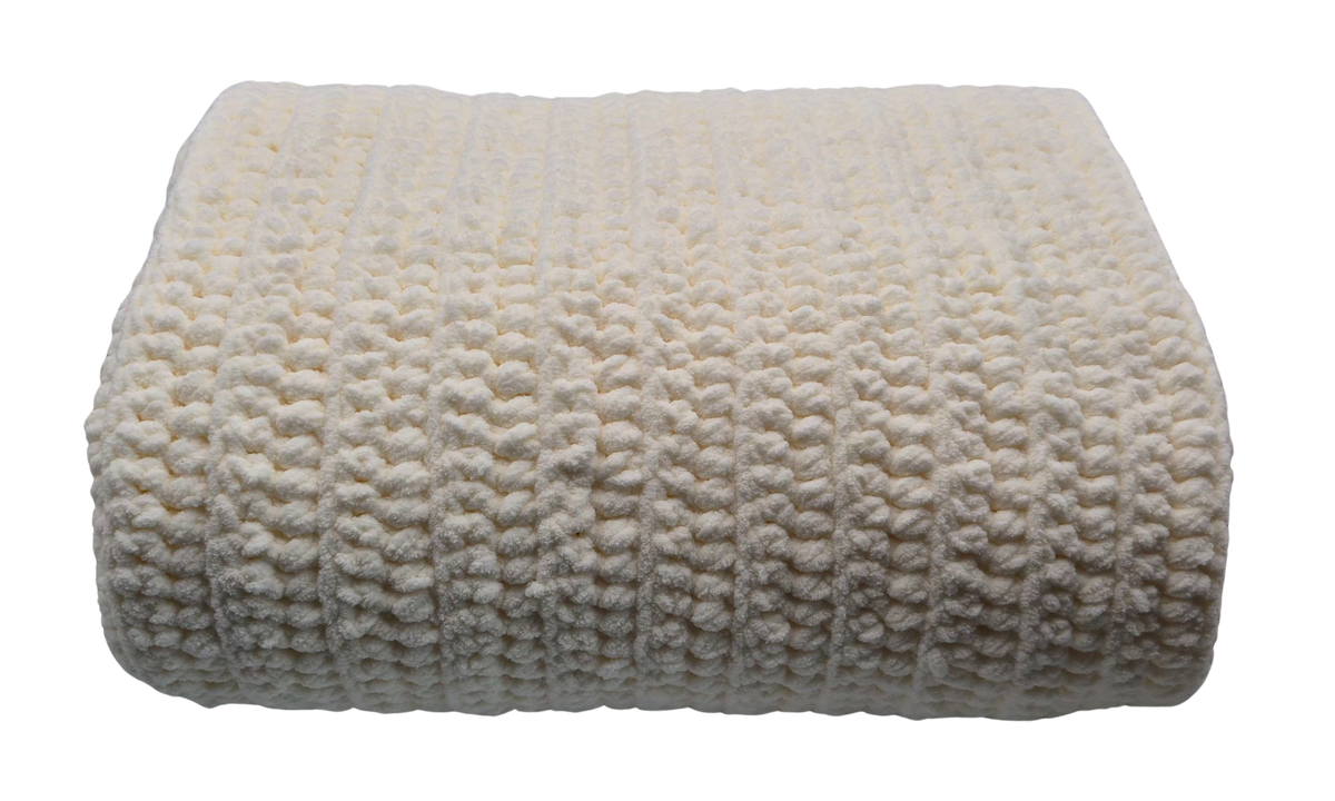 A folded cream-colored chunky crocheted baby blanket with a textured bumpy stitch pattern.