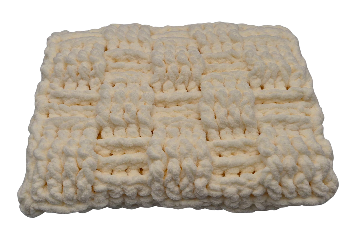 A chunky crocheted baby pillow in a warm cream color, featuring a textured basket weave pattern.