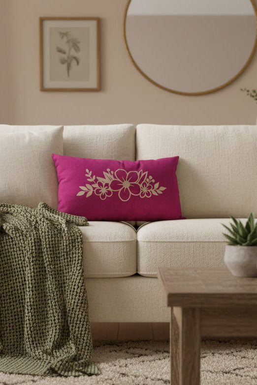 A rectangular magenta throw pillow with a vinyl floral pattern printed on the front, displayed on a sofa.